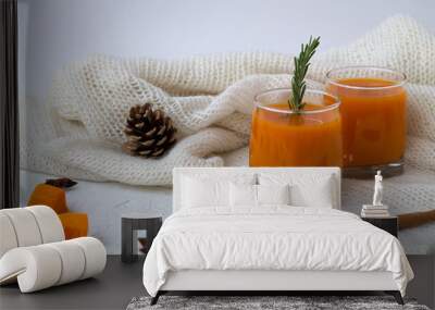 cocktail with sprig of rosemary and sticks of cinnamon on the warm white plaid on white table. glass of fresh pumpkin or oranges juice with slices of pumpkin, spices and winter decoration. Wall mural