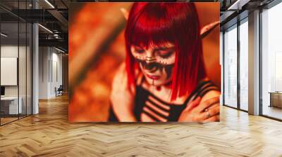 Girl cosplay in the image of a dark elf in a red wig portrait close-up. A woman with red lenses in her eyes and red hair in an elf costume with false ears and makeup. Dark elf outfit for Halloween. Wall mural