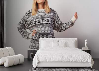 Russian girl in a knitted pullover on a white wall. Slav girl in a Turkish knitted New Year's sweater on a light wall. Christmas sweater with stars on a woman for a photo shoot Wall mural