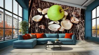 Close up shot of green apple with wooden table background and shells around it. Wall mural