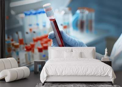 Technician holding blood tube test in the research laboratory / doctor hand taking a blood sample tube from a rack with machines of analysis in the lab background Wall mural