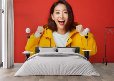 Surprised happy asian woman in sweater coat and looking at the camera yellow red colorful background concept Wall mural