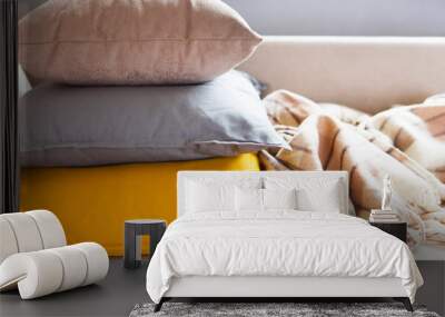 Cushions and plaid on the beige sofa close up with copy space. Sweet home and cozy concept Wall mural