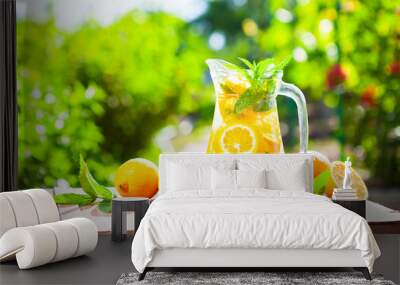 Summer fresh cold drink beverages. Ice Lemonade in the jug and lemons and orange with mint on table Wall mural