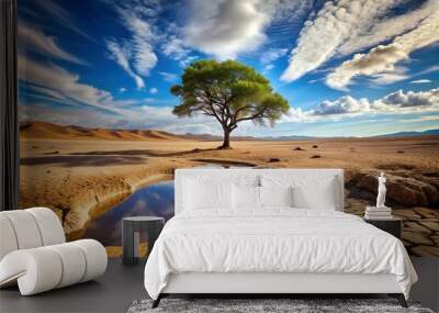 A desert landscape with cracked earth, a single tree, a water stream, and a vast blue sky, capturing nature's resilience. Wall mural