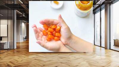 child holds a handful of vitamins for children in the palms. vitamin overdose, synthetic vitamins Wall mural