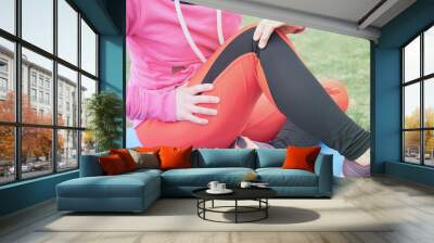 Female athlete suffering form running knee or kneecap injury during outdoor workout on dirt road. Wall mural