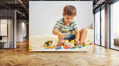 happy asian boy playing with colorful construction plastic blocks on white Bed at home. Wall mural