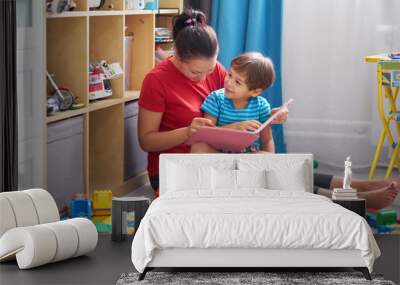 kid boy and his mother read a book on floor at home Wall mural