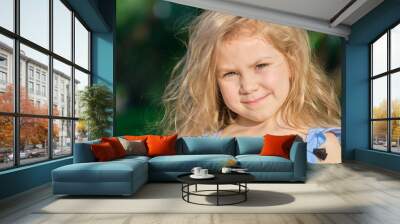 Little girl smiles at the camera. pretty girl posing for a photo and holding two green fresh apples in her hands Wall mural