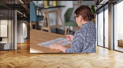 senior woman playing solitaire at home. Happy old lady plays an intellectual game Wall mural