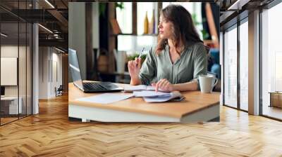 Young woman working from home office. Freelancer using laptop and the Internet. Workplace in living room. Wall mural