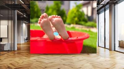 Closeup of little kid's legs in small red pool Wall mural