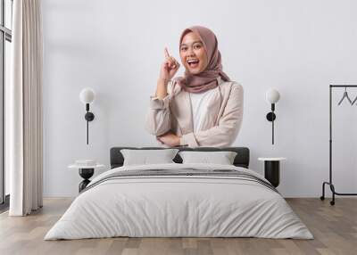 Portrait of excited Asian hijab woman in casual suit pointing up her forefinger and reminding something to do. Businesswoman concept. Isolated image on white background Wall mural