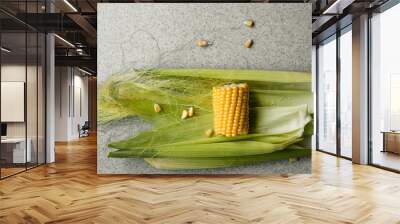 Pieces of ripe, young corn in leaves on a gray table. The view from the top. The concept of power. Wall mural