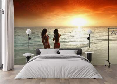 Two women enjoying sunset on beach Wall mural