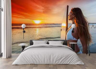 Woman on beach holding surfboard Wall mural