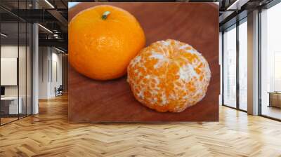 Comparison of orange fruit before and after peeled, served on wooden plate, on white background Wall mural