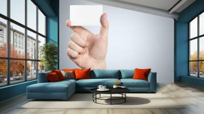 Hand holding a blank card or a ticket/flyer on gray background Wall mural