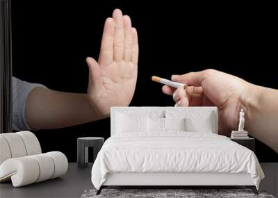 Hand refusing a cigarette offer, isolated on black background Wall mural