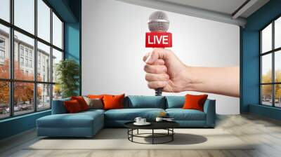 Male hand holding a microphone, isolated on grey background Wall mural