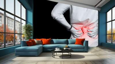 Man suffering from a lower back pain, isolated on black background Wall mural