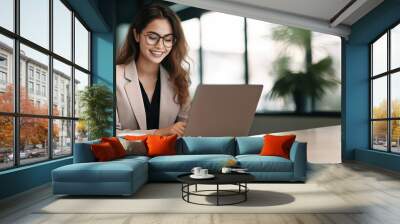 Professional female employee or a businesswoman using a laptop in a modern office. Copy space Wall mural