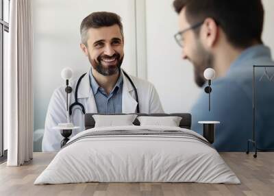 Smiling male doctor communicating with a patient in his medical office Wall mural