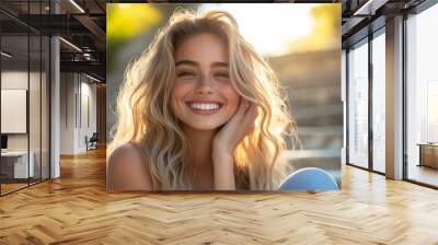 A cheerful young woman with flowing blonde hair, laughing on urban park steps Wall mural