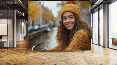 Happy young woman riding a bicycle near scenic city canal Wall mural