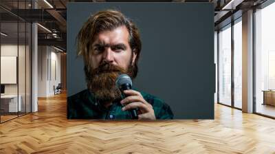 Bearded man in karaoke sings a song into a microphone. Male attends karaoke. Bearded man singing with microphone. Male singing with a microphones. Man with a beard holding a microphone and singing Wall mural