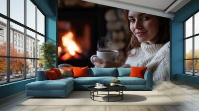 Cozy comfort  young woman by the fireplace with hot beverage amidst europe s energy crisis Wall mural