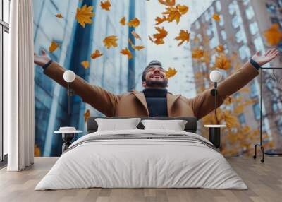 Joyful businessman celebrates success by tossing yellow maple leaves in city park with skyline view Wall mural