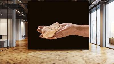 Old woman hand holding a pie, dough on a black background. Female hands holding raw dough on black background. Hands holding a finished clean dough. Hands holding dough ready for baking, closeup Wall mural