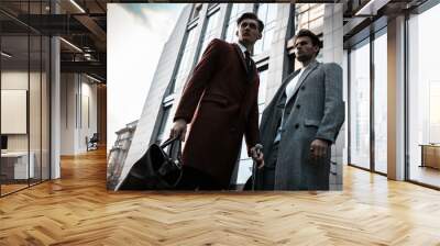 Two fashion men models posing on city street. Wearing in classic and casual closes. Suit, coat, shirt, sweater, boots and leather bag. Men model test near business center Wall mural