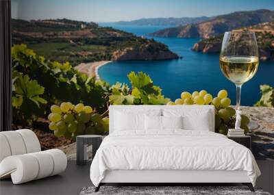 White wine glass is displayed alongside fresh grapes overlooking beautiful coastal vista Wall mural