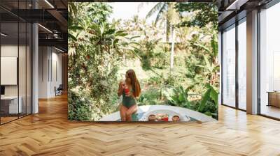 Happy caucasian  woman in swimsuit relaxing with cocktail and food in pool Wall mural