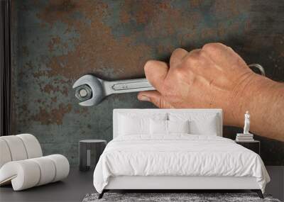 The hand unscrews the nut with a wrench. Wall mural