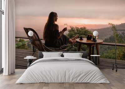 Young woman enjoying glass o white  wine on the roof by the mountain terrace  at sunset Wall mural