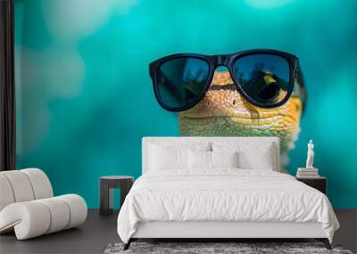 Close-up of a lizard in sunglasses with vibrant colors and a teal background. Wall mural