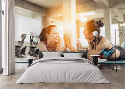 Beautiful asian women working out in gym together.Two attractive fitness girls doing push ups. Wall mural