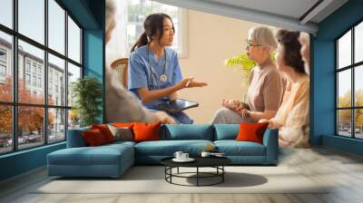 Group of asian senior people listening to young nurse. Psychological support group for elderly and lonely people in a community centre. Group therapy in session sitting in a circle in a nursing home. Wall mural