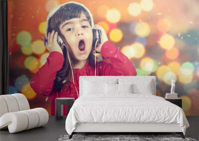 Portrait of a little Santa girl singing while listening to music. Defocused bokeh Christmas lights background Wall mural