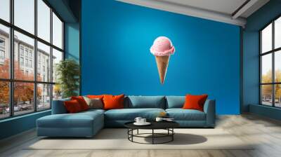 Pink ice cream scoop on a waffle cone against a blue background. Wall mural