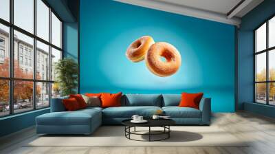 Two powdered donuts floating against a blue background. Wall mural