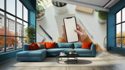 a woman using a smart phone at her desk. close up of young female's hands scrolling on phone at white desk. top view of woman holding smartphone on desk. white background. generative AI Wall mural