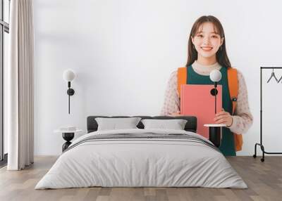 Happy young Korean female college student model holding copybooks isolated on white background. Smiling asian girl learner looking at camera, advertising for education. Wall mural