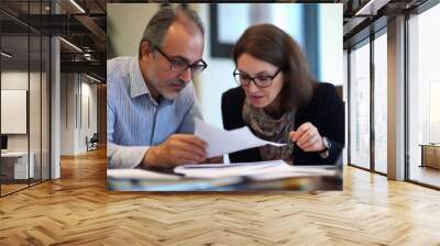 Two busy middle aged professional man and mature woman business leaders partners checking document financial report talking working together in office at corporate meeting. Wall mural