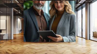 two happy busy business man and woman executives partners team working together standing in office using digital tablet in corporate cooperation on company project. Wall mural