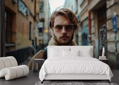 Fashionable young male with sunglasses posing in a city street, exuding trendy urban vibes Wall mural